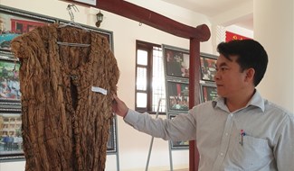 Ông Hồ Văn Phương và chiếc áo A Mưng trưng bày ở nhà văn hóa các dân tộc thiểu số. Ảnh: Hưng Thơ.