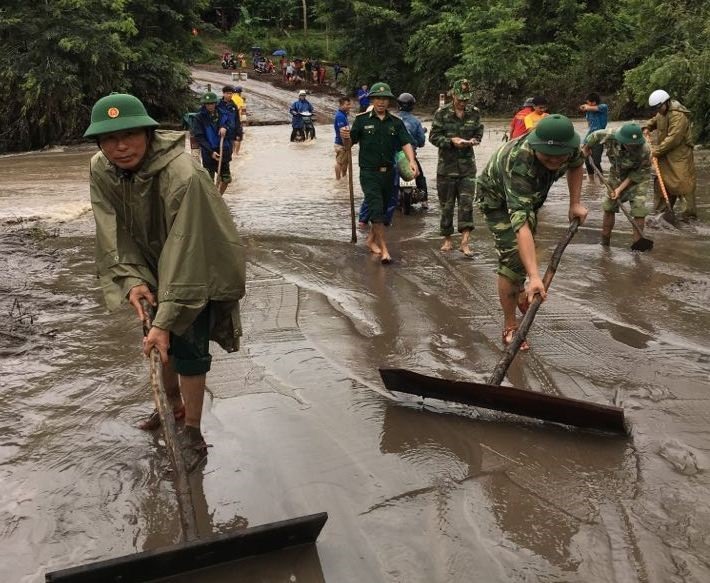 Lực lượng Biên phòng Quảng Trị phối hợp với chính quyền, người dân dọn dẹp các đoạn đường bị ngập, ùn tắc vì bùn đất do mưa lũ. Ảnh: Văn Anh.