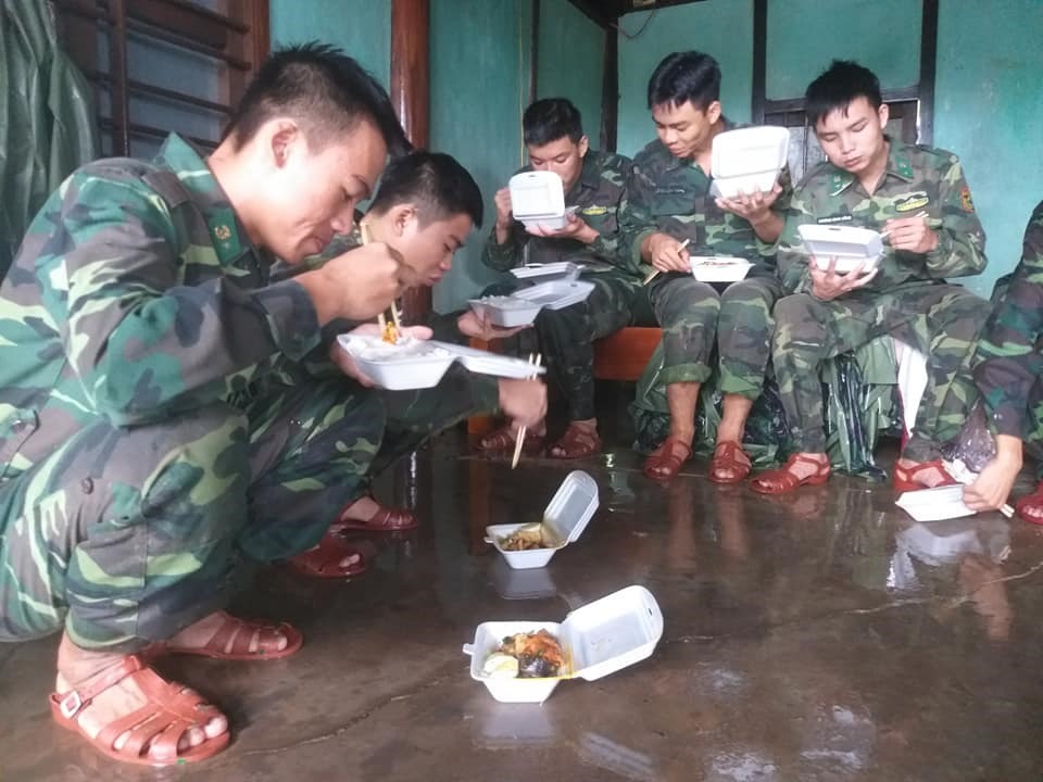 Bữa trưa của các chiến sĩ ngay tại “chiến trường” ngập lụt. Ảnh: Quang Thuyên.