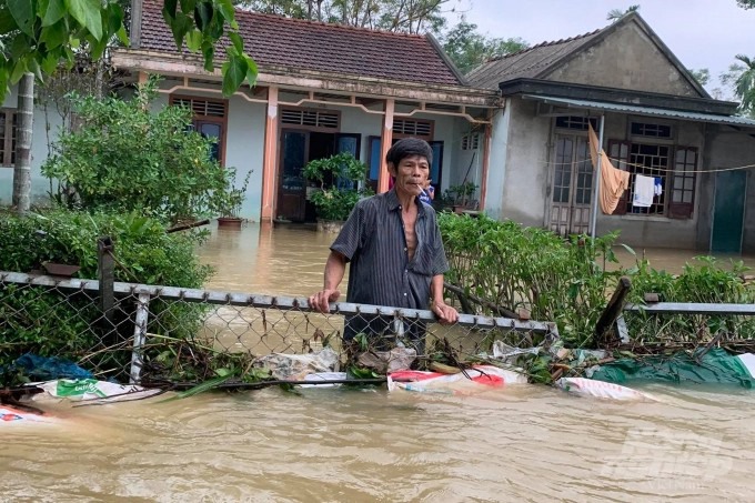 Một người dân ở huyện Hải Lăng đứng trước nhà khi nước lũ đã lên ngang lưng. Ảnh: Công Điền.