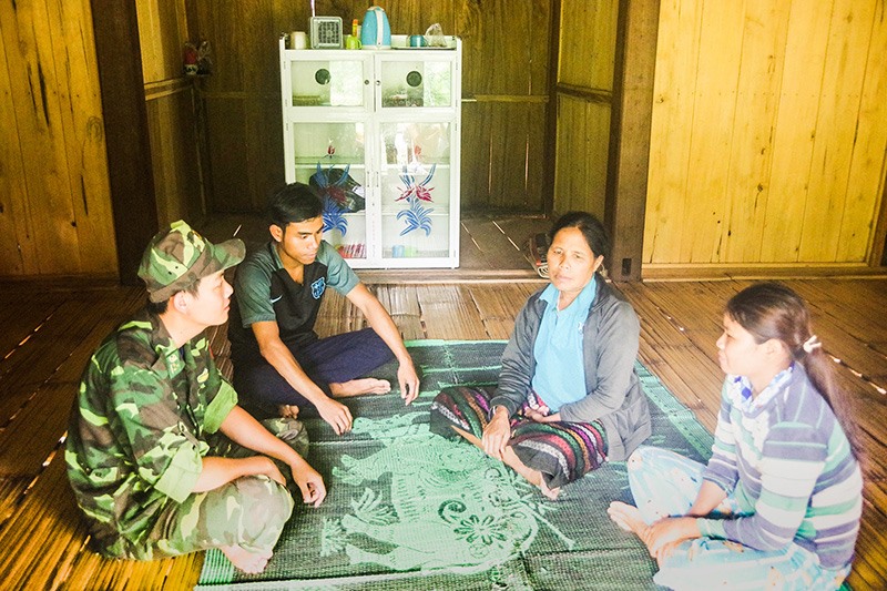 Bà Hồ Thị Lêm (thứ 2 từ phải sang) trò chuyện cùng cán bộ Đồn Biên phòng CKQT La Lay trong ngôi nhà đơn sơ của mình -Ảnh: N.T.P​