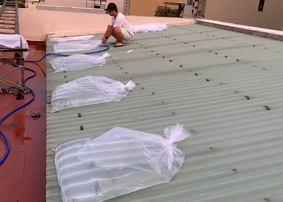 Người dân bơm nước vào túi nilon để chèn chống mái nhà. Đây là cách thức mới, dễ thực hiện và hiệu quả cũng tương tự chèn bao cát. Ảnh: Tr. Hiếu