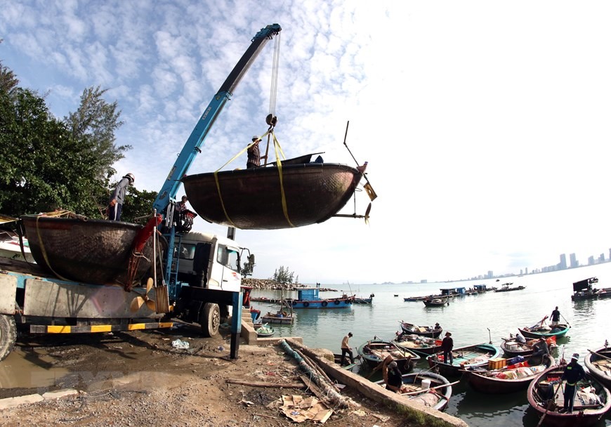 Xe cần cẩu đưa các phương tiện đánh bắt thủy sản của ngư dân Đà Nẵng lên bờ, vận chuyển vào sâu đất liền để tránh bão số 9. (Ảnh: Trần Lê Lâm/TTXVN)