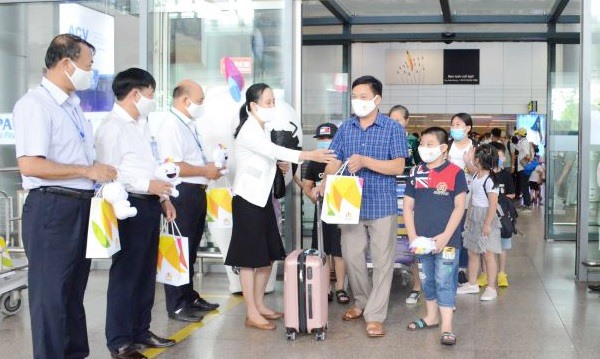 Tại Sân bay quốc tế Đà Nẵng, Đại diện Sở Du lịch Đà Năng tặng quà cho đoàn du khách đầu tiên trở lại du lịch thành phố sau dịch COVID-19. Ảnh: TTXVN.