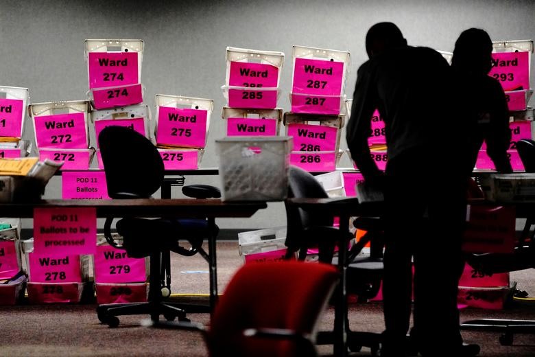 Ảnh trái - Các ô trống từ các khu vực bỏ phiếu của Milwaukee vào đêm của ngày bầu cử khi các lá phiếu vắng mặt được kiểm tại. Và những người giám sát công tác kiểm phiếu đeo khẩu trang phòng tránh virus COVID-19 lây nhiễm. (Ảnh phải). Ảnh: Reuters