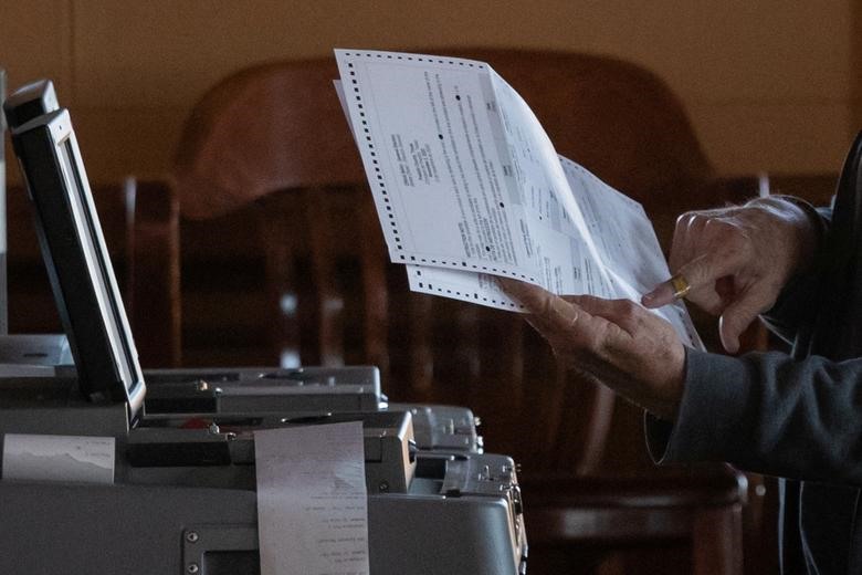 Một nhân viên kiểm tra chỉ vào một bức thư trong lá phiếu trong khi quét các phiếu bầu cho cuộc bầu cử Tổng thống Mỹ năm 2020 ở Marfa, Texas.  Ảnh: Reuters