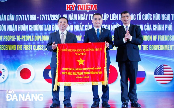 Phó Chủ tịch UBND thành phố Hồ Kỳ Minh (bìa phải) trao Cờ thi đua của Chính phủ cho Liên hiệp Các tổ chức hữu nghị thành phố. Ảnh: XUÂN DŨNG