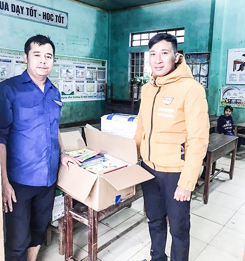 Anh Trần Hải Nam (trái) trao sách vở hỗ trợ các trường học vùng cao bị ảnh hưởng sau lũ - Ảnh: NVCC​