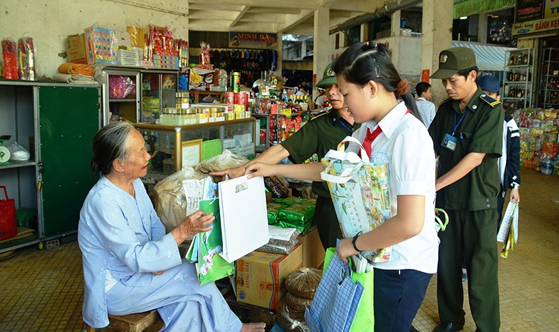 Học sinh phát túi giấy cho các tiểu thương tại chợ Đông Hà để tuyên truyền hạn chế dùng túi nilon -Ảnh: ĐV​