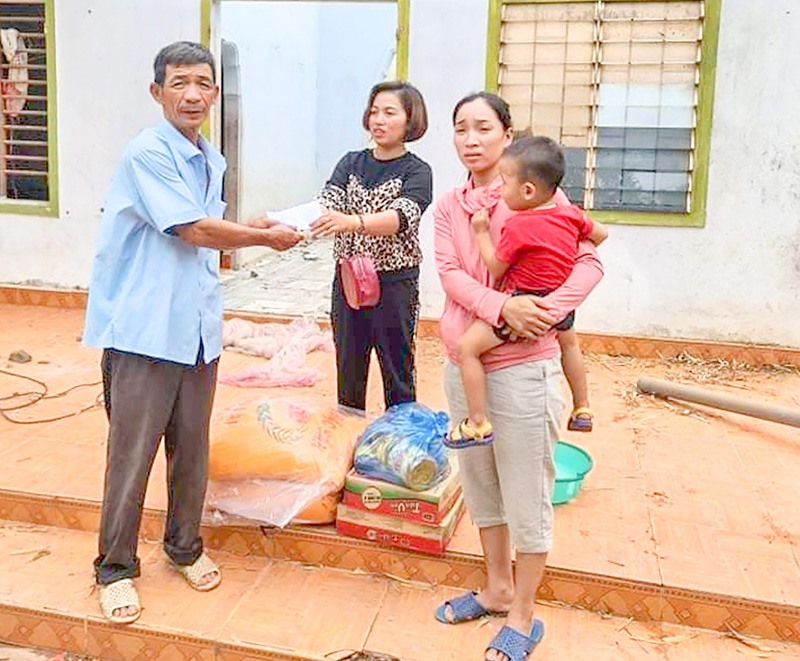 Chị Loan (đứng giữa) trao quà hỗ trợ cho gia đình có nhà bị tốc mái do bão - Ảnh: K.S​