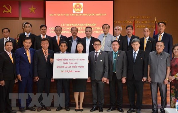 Chủ tịch Trịnh Cao Sơn (đứng thứ 4, hàng đầu) cùng Ban chấp hành Tổng Hội người Việt Nam toàn Thái Lan trao tượng trưng tiền ủng hộ đồng bào miền Trung. (Ảnh: Ngọc Quang/TTXVN)