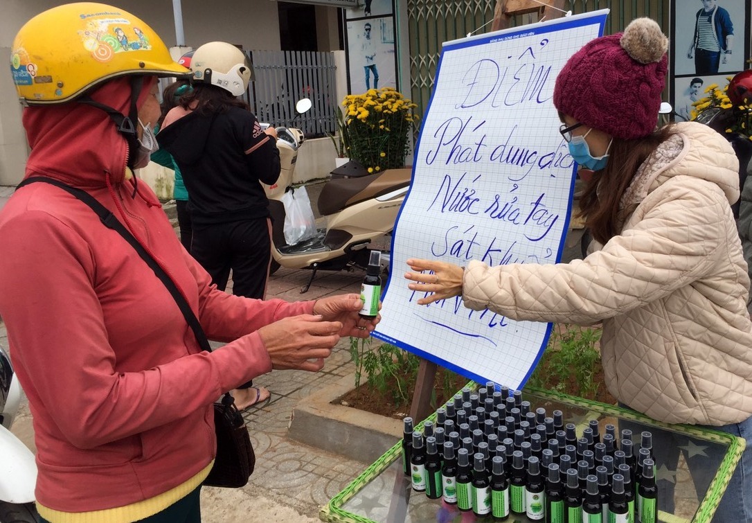 Chị Hương tặng và chỉ dẫn cho người dân cách dùng nước rửa tay sát khuẩn. Ảnh: TH.