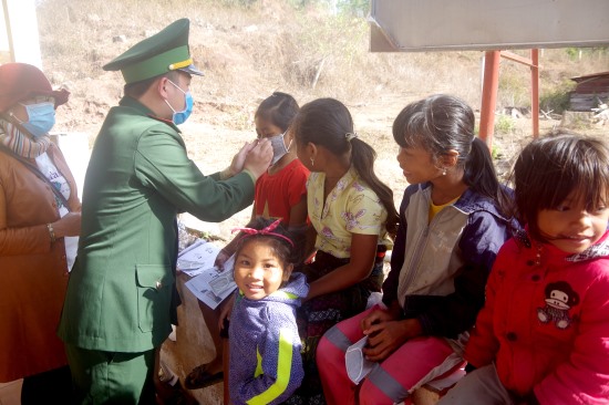 Thượng úy Lê Thừa Văn phát khẩu trang miễn phí và hướng dẫn các cháu nhỏ trên địa bàn sử dụng để phòng, chống dịch Covid-19. Ảnh: Xuân Thế