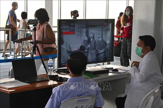 Nhân viên kiểm tra thân nhiệt hành khách bằng máy quét thân nhiệt tại sân bay quốc tế Wattay ở Vientiane, Lào ngày 11/3/2020, trong bối cảnh dịch COVID-19 lan rộng. Ảnh: AFP/TTXVN