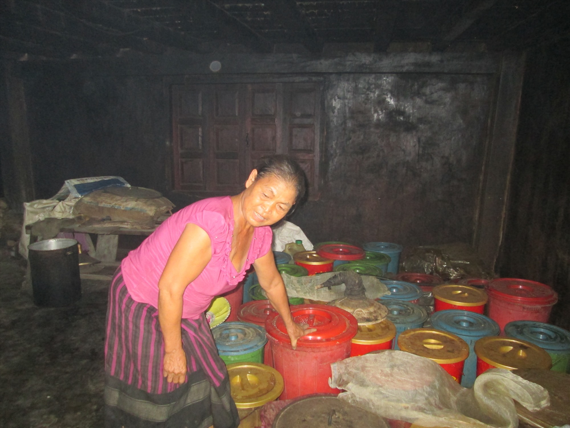 Bà Hồ Thị Mom bên những thùng vật liệu nấu rượu đang ủ cho lên men