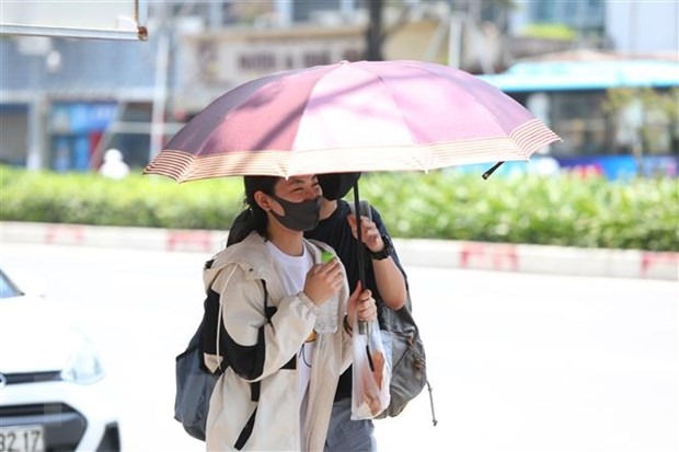 Người dân ra đường ngoài đeo khẩu trang còn che ô để tránh nắng và tia UV gây hại. (Ảnh: Thành Đạt/TTXVN)