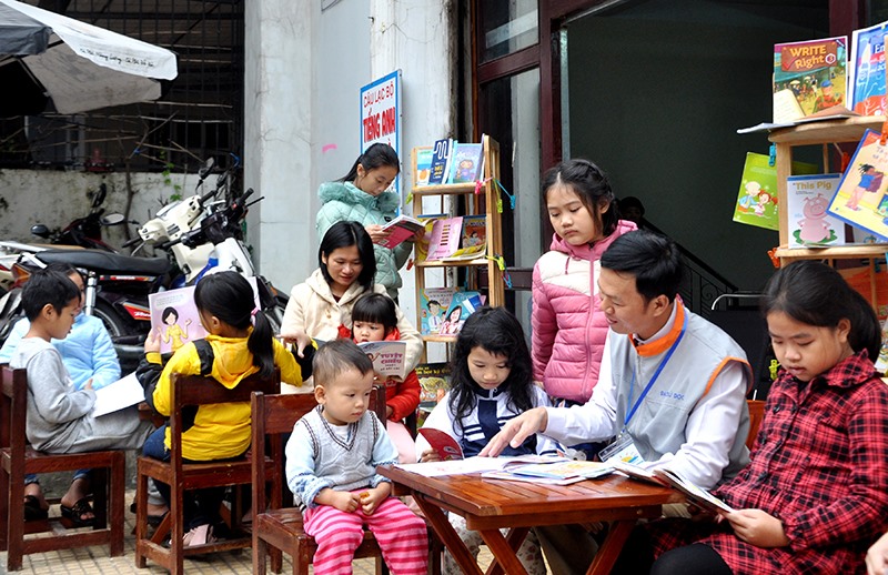 Vợ chồng thầy Phan Văn Hiền đọc sách cùng các em nhỏ. Ảnh: Q.H