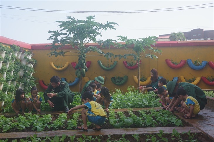 Các bé mẫu giáo cùng cô giáo và các cán bộ Biên phòng chăm sóc vườn rau. Ảnh: Nguyễn Thành Phú