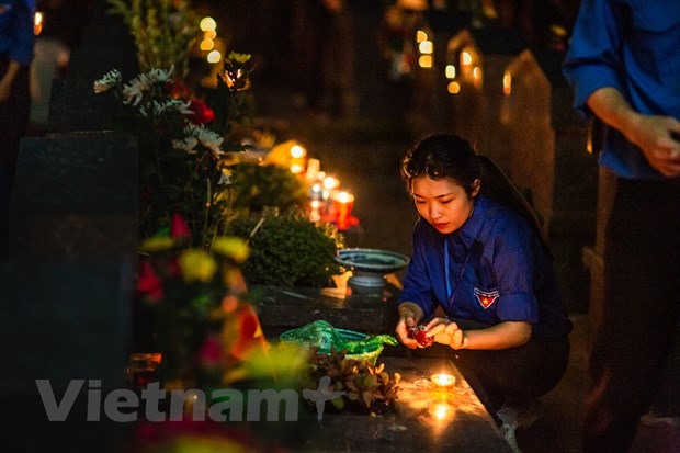 Các đoàn viên thanh niên luôn giữ cho những ngọn nến được cháy sáng mãi trong suốt buổi lễ. (Ảnh: Quang Hưng/Vietnam+)