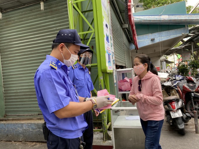 Bảo vệ chợ Cồn điền thông tin vào phiếu giúp người dân trước khi vào chợ.