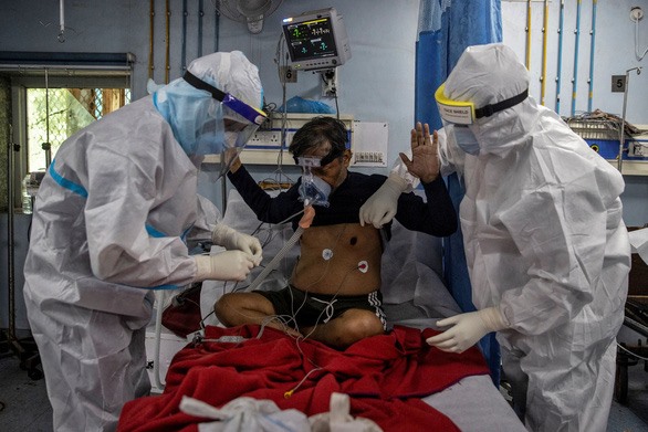 Một bệnh nhân COVID-19 ở Ấn Độ được hai nhân viên y tế hỗ trợ khi đang nằm trong phòng chăm sóc đặc biệt. Ảnh: Reuters.