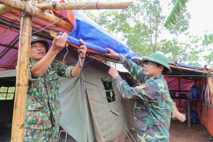 Thượng úy Nguyễn Văn Bình cùng đồng đội sửa lại tấm bạt vừa che mưa, lấy nước sinh hoạt.