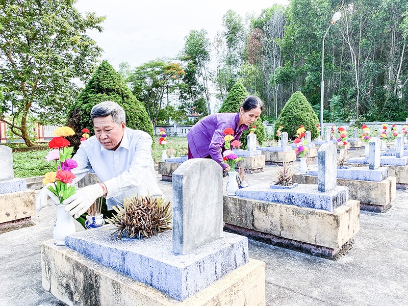 Người dân chăm sóc các ngôi mộ liệt sĩ trong nghĩa trang xã Cam Thủy. Ảnh: TP