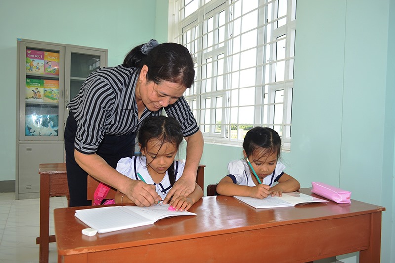 Cô giáo Nguyễn Thị Thanh Tâm nắn nót từng nét chữ cho các em học sinh điểm trường Càng -Ảnh: Đ.V​