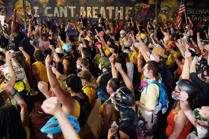 Những người biểu tình diễu hành qua một bức tranh trên tường ghi lại những lời cuối cùng của George Floyd - “I can't breath” (Tôi không thở được). Ảnh: Getty Images