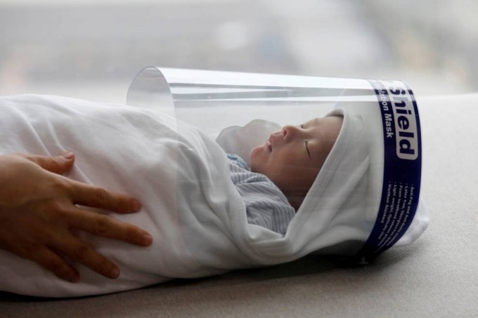 Một em bé sơ sinh đeo tấm chắn bảo vệ để phòng dịch Covid-19 tại Hà Nội, Việt Nam. Ảnh: Reuters