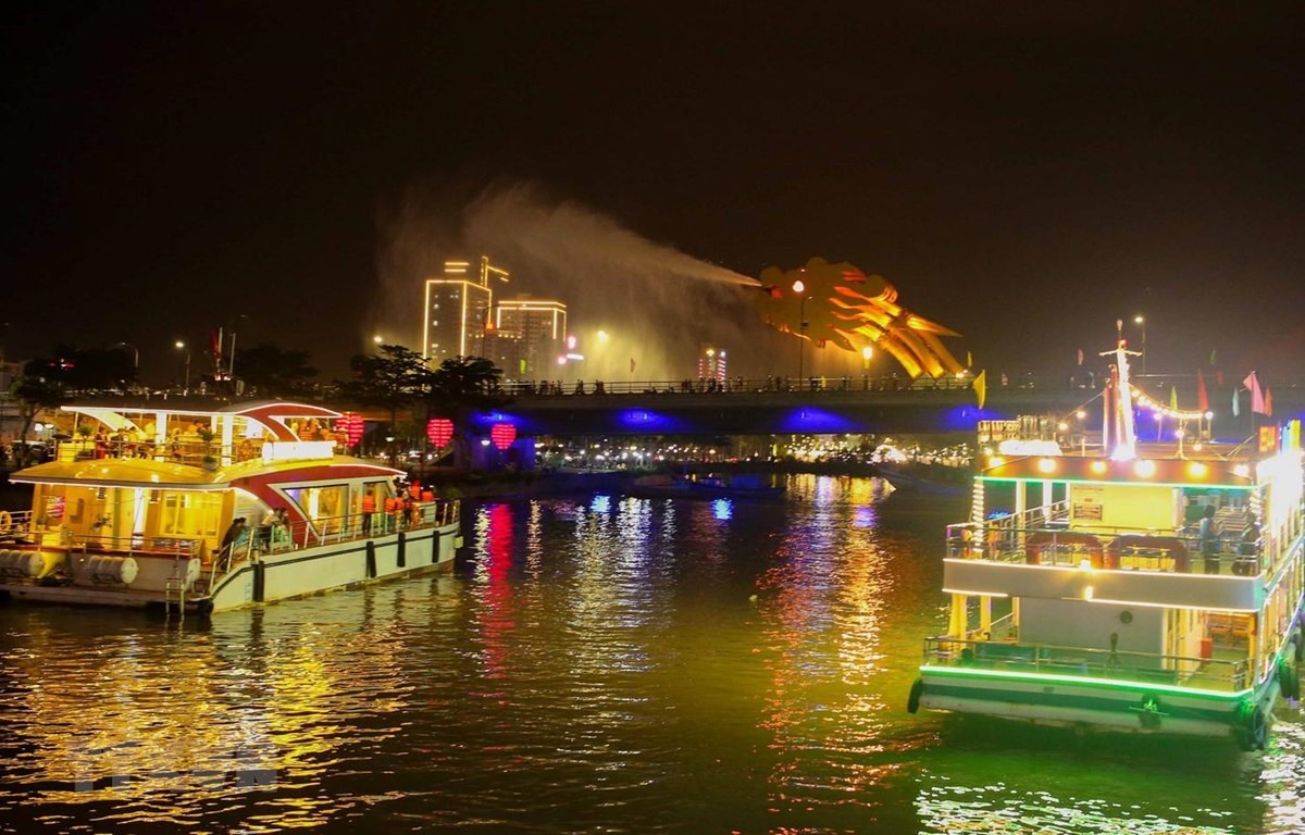 Các du thuyền đưa du khách ngắm cầu Rồng phun nước trong tour du lịch miễn phí thưởng ngoạn ngắm sông Hàn về đêm. (Ảnh: Trần Lê Lâm/TTXVN)