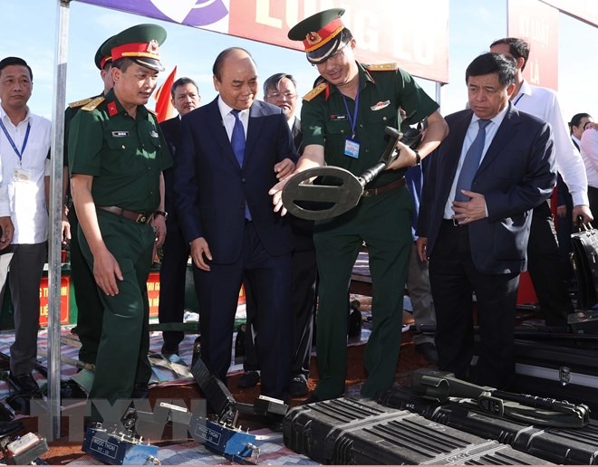 Thủ tướng Nguyễn Xuân Phúc nghe các đơn vị quốc phòng giới thiệu về các thiết bị rà phá bom mìn, đảm bảo an toàn trong quá trình thi công dự án. (Ảnh: Thống Nhất/TTXVN)