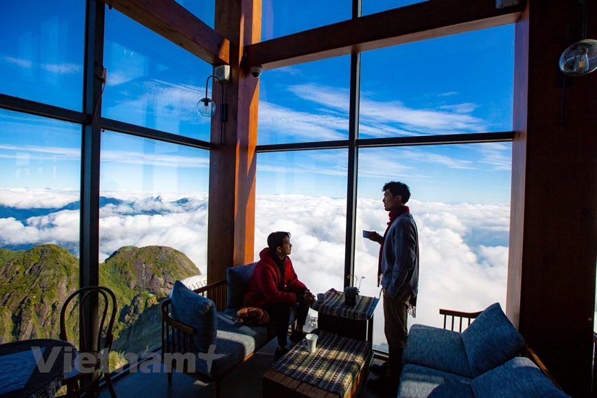 Ngay dưới chân cột cờ trên đỉnh Fansipan có một quán càphê sân mây nhỏ xinh, du khách có thể vừa hàn huyên vừa ngắm mây vờn qua cửa sổ. (Ảnh: Minh Sơn/Vietnam+)
