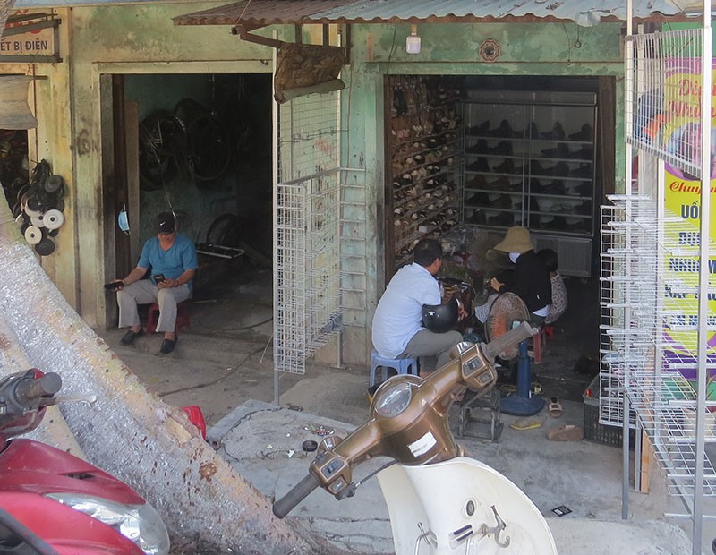 Khách hàng đợi sửa giày tại cửa hàng của chị Lê Thị Trang -Ảnh: KHÁNH LINH