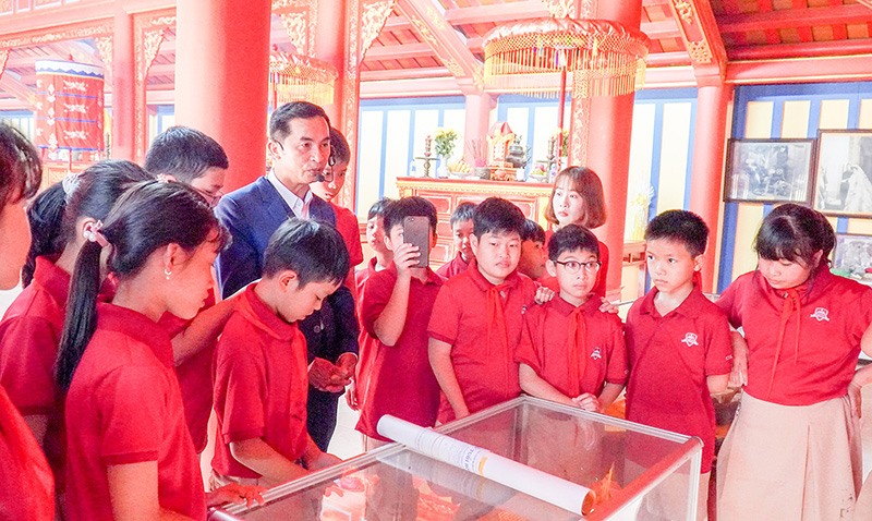 Học sinh lắng nghe anh Nguyễn Văn Hiếu giới thiệu về Đền thờ Vua Hàm Nghi tại Di tích lịch sử Quốc gia Thành Tân Sở - Ảnh: L.T