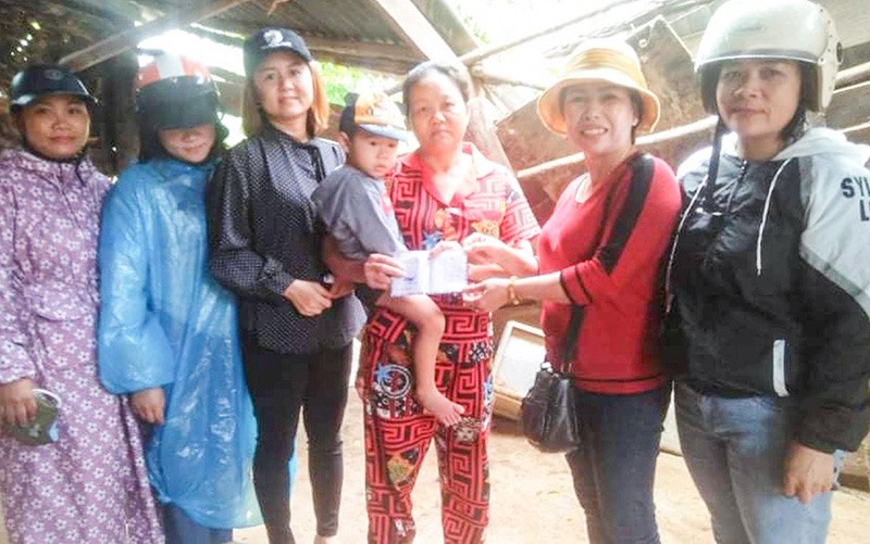 Các thành viên Nhóm Thiện nguyện Tân Long trao hỗ trợ cho phụ nữ nghèo bị thiệt hại do thiên tai - Ảnh: N.T