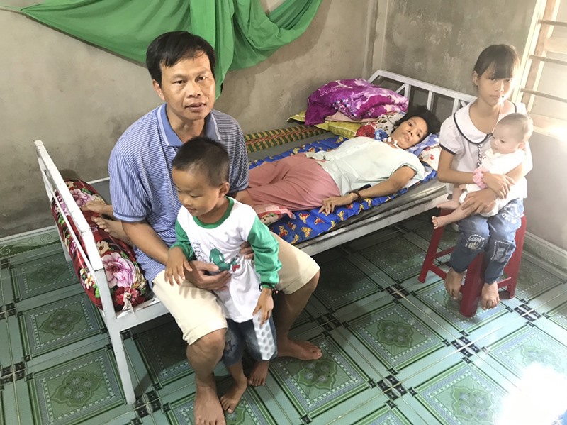 Anh Trần Duy Quyền chăm sóc người vợ bị bại liệt và 3 đứa con thơ dại - Ảnh: H.T​