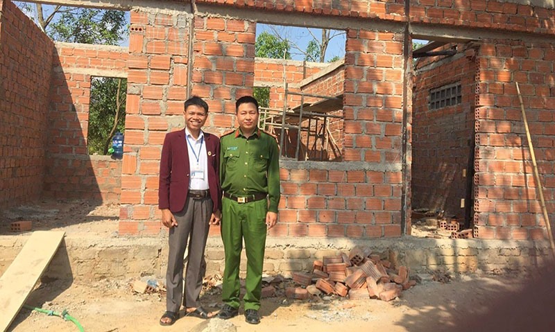 Anh Hồ Văn Minh (bên trái) trước công trình trụ sở và nhà ở lực lượng công an xã do gia đình anh hiến đất xây dựng sắp hoàn thành - Ảnh: N.T​