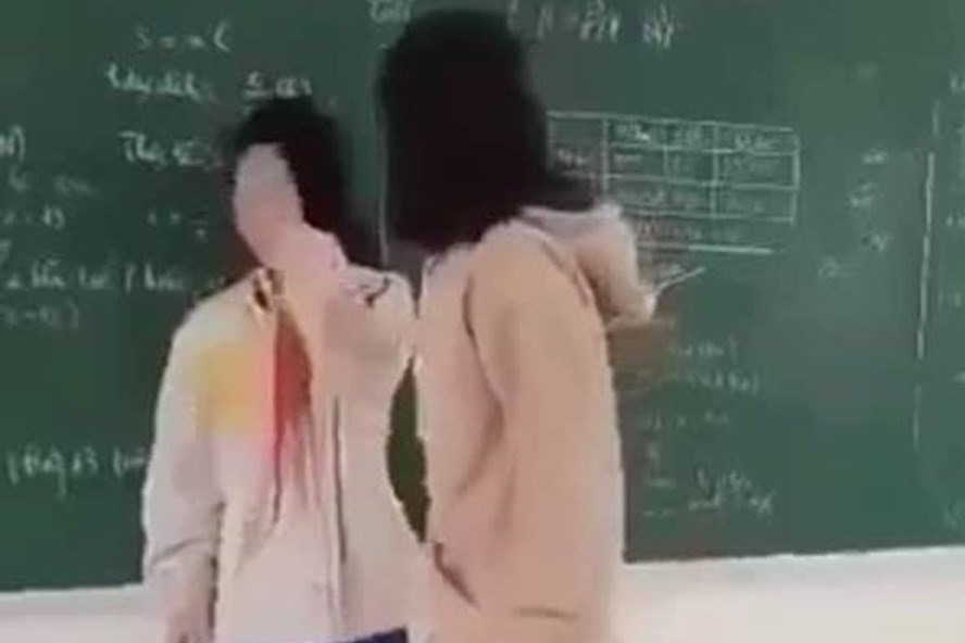 Nữ sinh B (bên phải ảnh) đánh bạn cùng lớp ngay trên bục giảng. Ảnh chụp video.