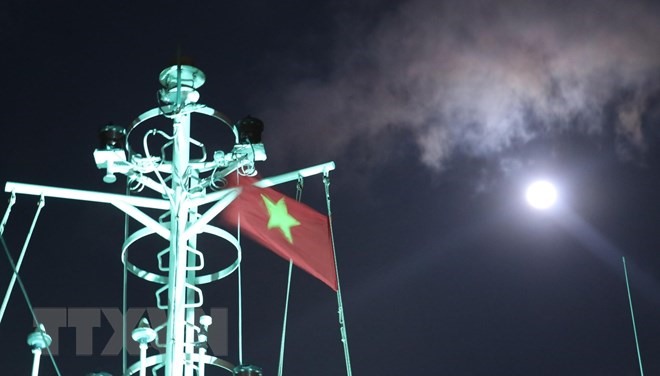 Cờ Tổ quốc trên nóc tàu Trường Sa 571 tung bay phấp phới dưới ánh trăng khi tàu đi trên vùng biển gần đảo Song Tử Tây – quần đảo Trường Sa (huyện Trường Sa, tỉnh Khánh Hoà). (Ảnh: Sỹ Tuyên/TTXVN)