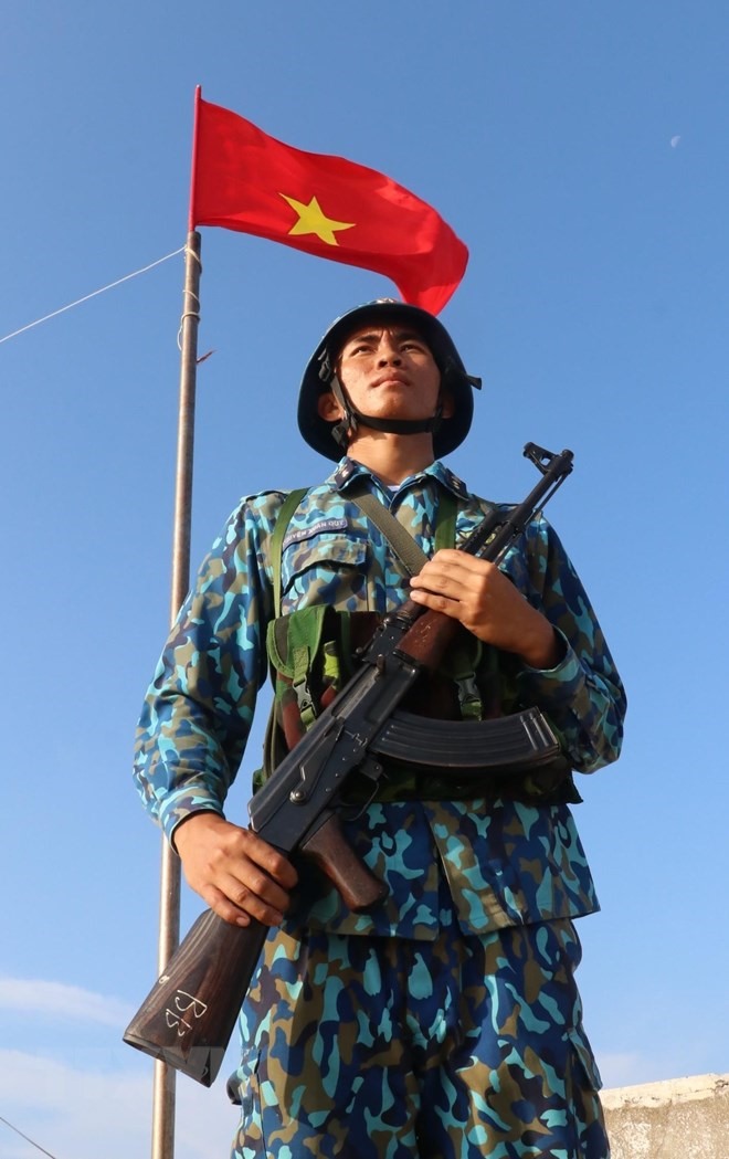 Chiến sỹ Nguyễn Xuân Quý - đảo Đá Tây A (quần đảo Trường Sa) nghiêm trang đứng gác dưới cờ Tổ quốc. (Ảnh: Sỹ Tuyên/TTXVN)