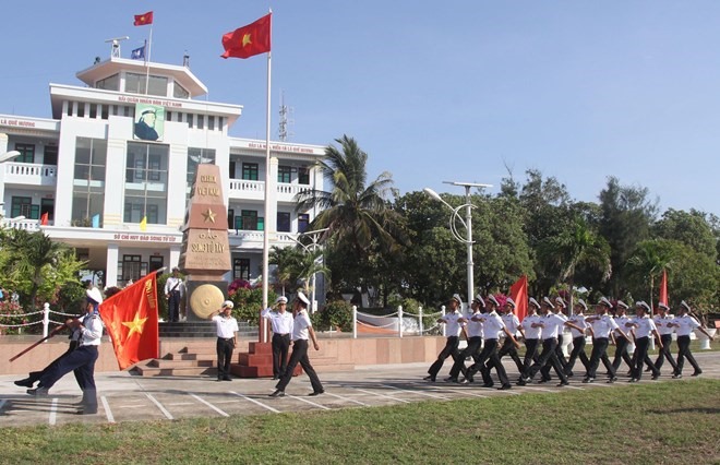 Đoàn duyệt đội ngũ mang lá 'Cờ Quyết thắng đảo Song Tử Tây' đi ngang qua cột mốc đảo Song Tử Tây trong lễ chào cờ trên đảo ngày 28/4/2021. (Ảnh: Sỹ Tuyên/TTXVN)