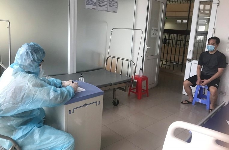 Điều tra viên mặc đồ bảo hộ làm việc với bệnh nhân Đào Duy Tùng trong khu cách ly. Ảnh: Công an cung cấp.