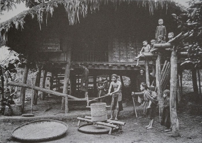 Trẻ em trong một gia đình người Thổ thuộc phủ Yên Bình (Yên Bái) đang xem người lớn xay thóc bằng tay và giã gạo bằng chân