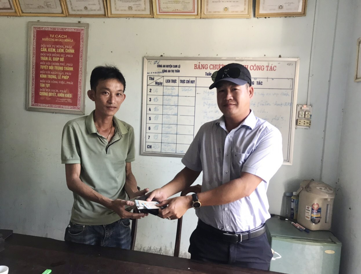 Anh Nguyễn Việt Dũng (đội mũ) trao trả lại số tiền cùng giấy tờ cho người đánh rơi- Ảnh: Lê Trường
