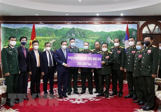 Phó Thủ tướng, Bộ trưởng Quốc phòng Lào trao số tiền 200.000 USD ủng hộ Quỹ phòng, chống COVID-19 của Việt Nam cho Đại sứ Việt Nam tại Lào Nguyễn Bá Hùng. (Ảnh: Phạm Kiên/TTXVN)