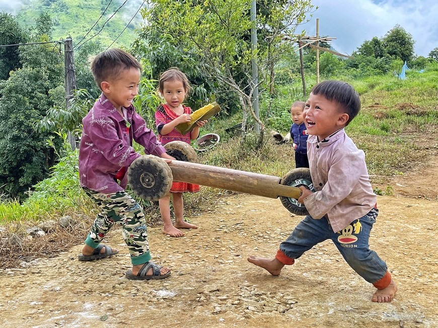 Các em nhỏ ở xã Sin Suối Hồ, huyện Phong Thổ, tỉnh Lai Châu háo hức khi được các anh lớn trong nhà chế cho chiếc 'ôtô 3 bánh.' (Ảnh: Mai Mai/Vietnam+)