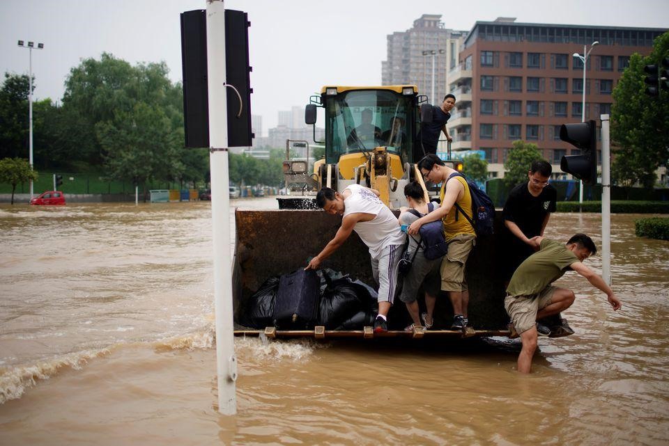 Người dân Trịnh Châu phải “quá giang” bằng máy xúc do nước lũ dâng cao. Ảnh: Reuters