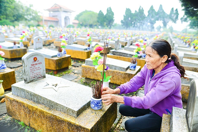 Bà Trần Thị Nguyệt thành kính dâng hương lên từng phần mộ các anh hùng liệt sĩ -Ảnh: N.T