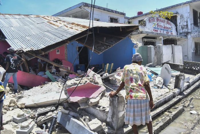Một phụ nữ đứng trước ngôi nhà bị phá hủy sau trận động đất ở Les Cayes, Haiti, hôm 14/8. Ảnh: AP
